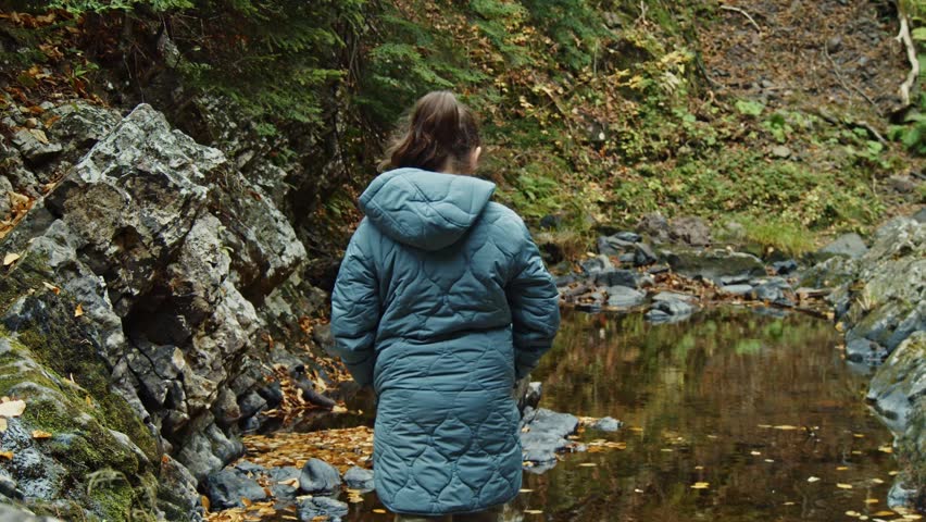 An Eight-Year-Old Girl Stands Still, Watching Waterfalls Cascade In A Mountain Forest. Her Warm Autumn Jacket Keeps Her Comfortable As She Takes In The Beautiful Surrounding Autumn Foliage.