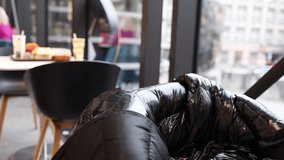 A cozy indoor scene in a modern cafe, with a shiny black jacket draped over a chair and a tray of food visible in the background. The setting feels warm and inviting. - Powered by Shutterstock - Get 15% off with code: PIKWIZARD15