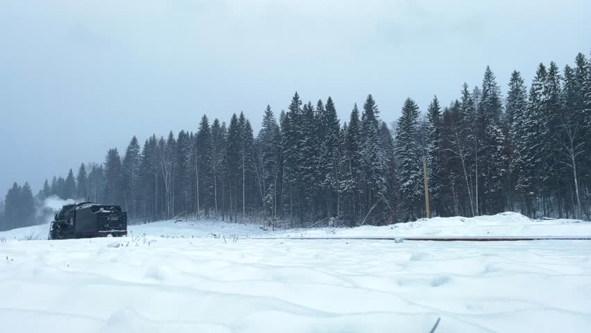black retro steam locomotive traveling through the snow-covered forests of Russia during winter