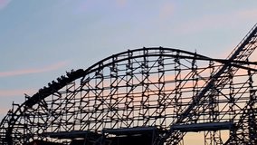 Silhouetted Roller Coaster at Sunset, A thrilling wooden roller coaster silhouetted against a colorful sunset sky - Powered by Shutterstock - Get 15% off with code: PIKWIZARD15