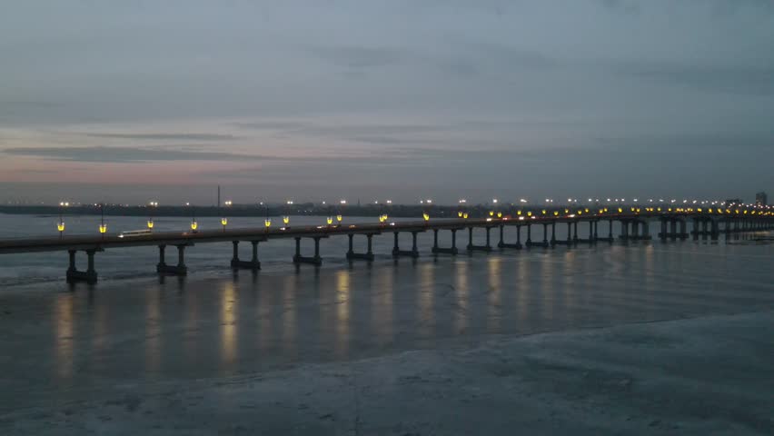 The night bridge with lanterns is reflected in water on the Dnipo River, in Dnepr city, Ukraine. Evening, morning river landscape in big city.