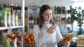 European teen girl customer at shop scan QR code on peach juice bottle using phone camera. Client study composition, manufacturer information of product using application. Visitor examines product - Powered by Shutterstock - Get 15% off with code: PIKWIZARD15