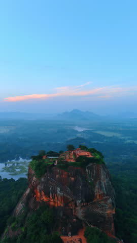 View of the unusual rounded huge bare rock with vegetation on top. Ruins of ancient fortress locate on the mountain among the greenery. Sigiriya, Sri Lanka from top view. Vertical video.