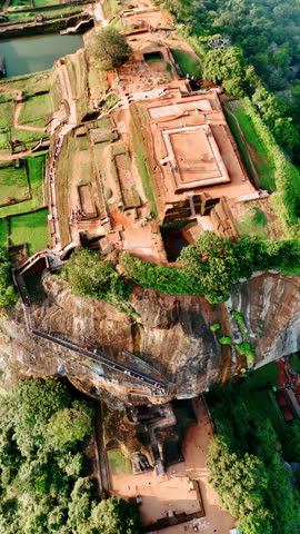 Ruins of Sigiriya surrounded by lush greenery. People walk by the famous landmark of Sri Lanka. Top view. Vertical video.