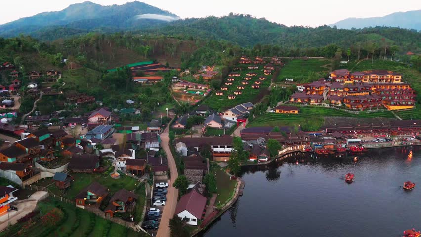Aerial fly above Ban Rak Thai highland village, lake, valley surrounded by hills and tea plantations at Mae Hong Son