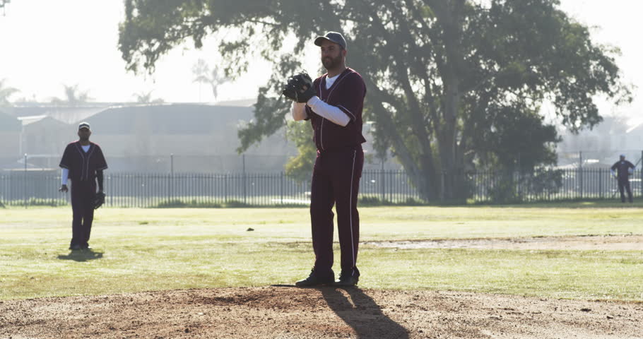 Multiracial male baseball players playing baseball, throwing the ball on a pitch, slow motion. sports, activity, teamwork, competition and baseball.