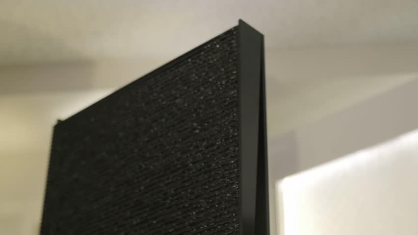 A small waterfall-like interior decoration of a black wall. Water is running down, providing a healing and spiritual atmosphere and sound, reflecting room lights.