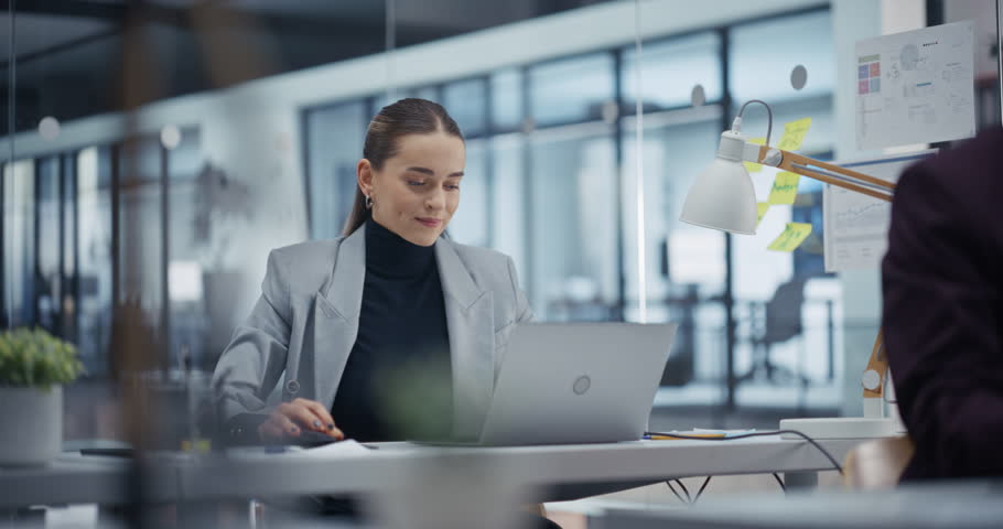 Young Professional Analyzing Business Data on Her Laptop Computer, Striving for Success. Suddenly, Female Manager Erupts in Celebration, Marking a Significant Achievement with a Fist Pump and Smile