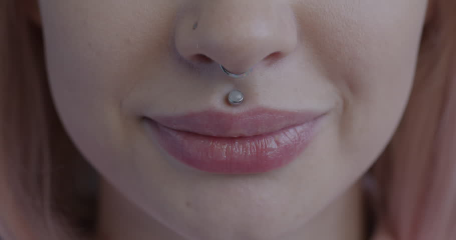 Close-up portrait of young lady's mouth with piercing smiling expressing joy. Human body part and positive emotion concept.