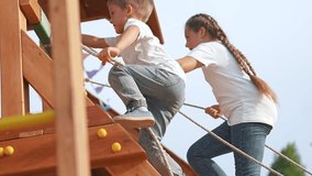 Happy Kid climbing rope in park playground. Kid enjoys active play on sunny day. Pulling rope, developing strength and coordination. Fun outdoor activity for kid in park. Happy childhood play in park. - Powered by Shutterstock - Get 15% off with code: PIKWIZARD15