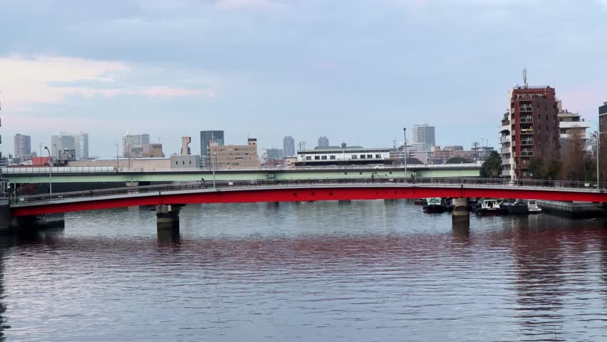 Scenic red bridge over river with Tokyo city skyline in Harumi, Japan