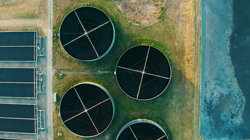 Top-down view of circular sedimentation tanks at wastewater treatment facility. Aerial view of modern sewage treatment plant with circular storages and sedimentation pond. Sustainable water management