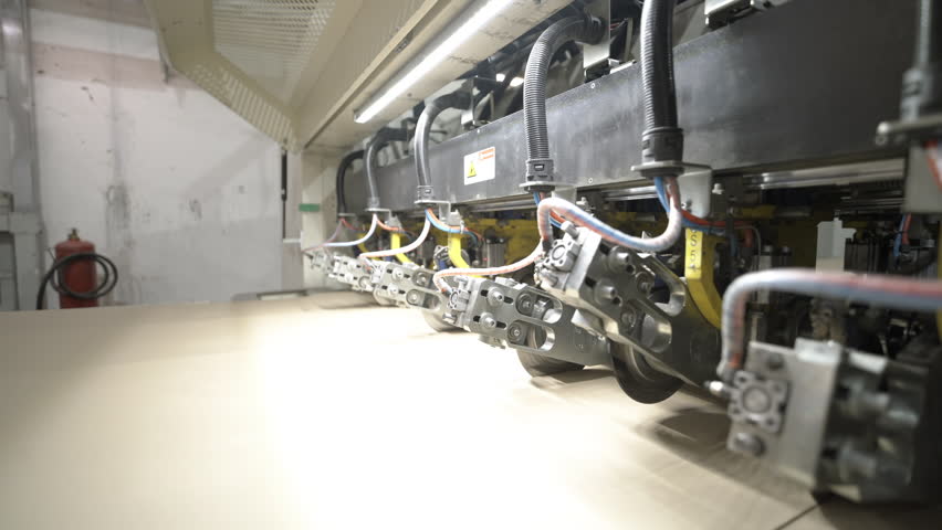 Special machines for processing cardboard web in workshop. Industrial equipment creates structure of material using production mechanisms