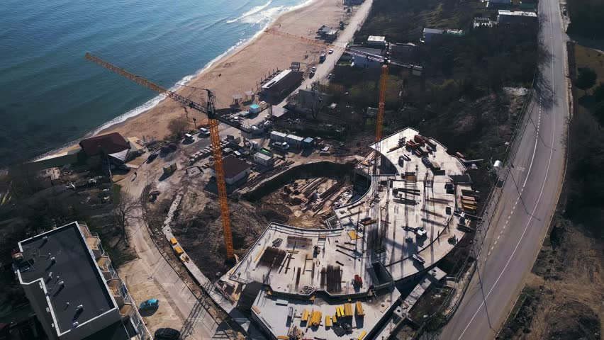 New hotel or residential complex under construction on the picturesque Kabakum Beach near Varna, Bulgaria. Tower cranes, metal structures, and the seaside view define this vibrant sunny worksite