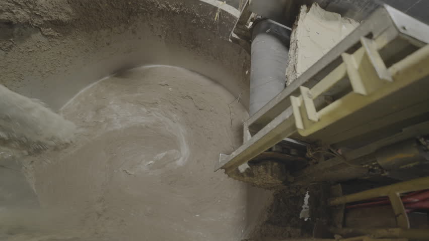 Raw material falls into tank with solution to soak material. Bale of waste paper moves on conveyor belt to container for processing in plant