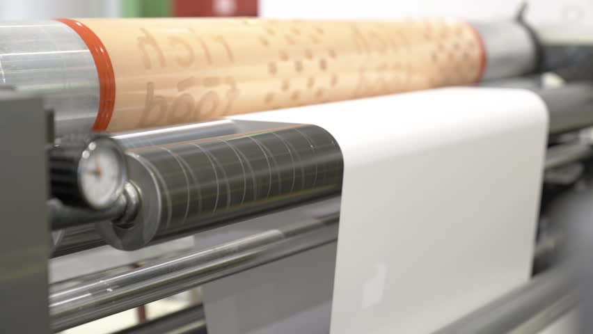 Industrial machine creates printed structure on cardboard web. Plant workshop contains large machine for forming pattern on finished product