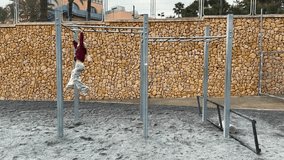 Young girl wearing christmas outfit having fun moving forward on monkey bars at a playground. Wide shot - Powered by Shutterstock - Get 15% off with code: PIKWIZARD15