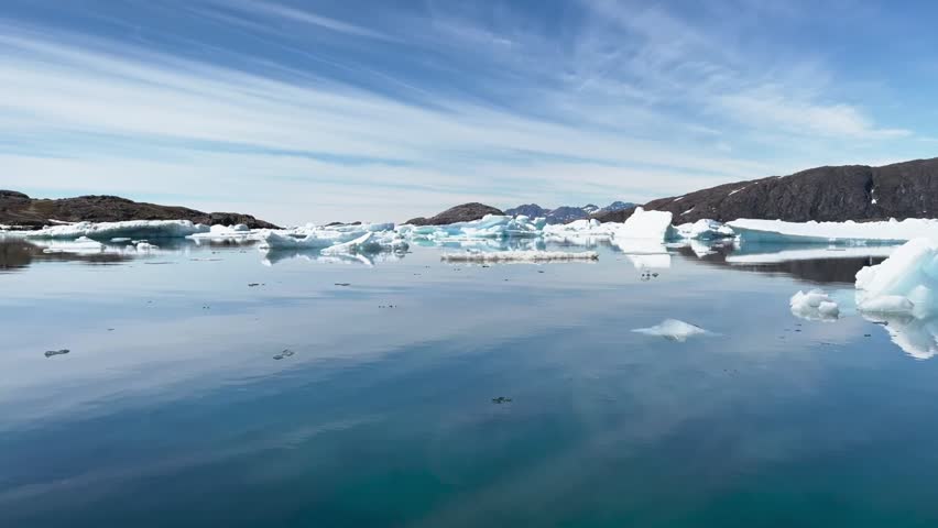 Melting icebergs by the coast of Greenland, on a beautiful summer day - Melting of a iceberg and pouring water into the sea - Greenland