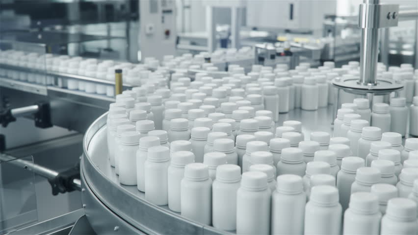 White Plastic Bottles Filled with Pills on Rotary Conveyor at Pharmaceutical Production Plant. Medication Manufacturing Process at Pharmaceutical Drug Factory 