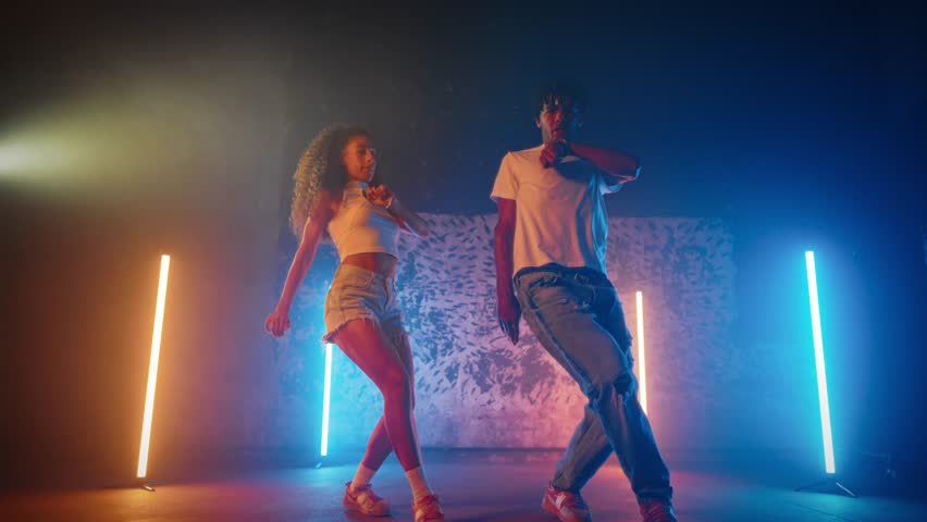 Full-length portrait of couple of black dancers performing dancehall on stage. African American man and woman enjoying rhythm of ethnic music and dancing, modern choreographic sequences and music