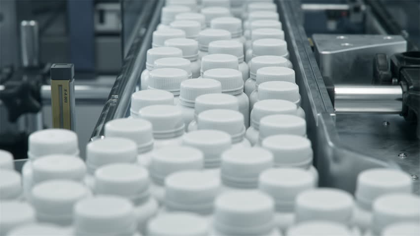 Close-up of Plastic Bottles with Medication Pills on Conveyor at Pharmaceutical Production Plant. Medication Manufacturing Process at Pharmaceutical Drug Factory 