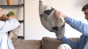 Cheerful diverse married couple in love sitting on sofa in living room at home. Millennial pretty mixed race wife and Caucasian husband have fun playing fighting with pillows laughing enjoying free
 - Powered by Shutterstock - Get 15% off with code: PIKWIZARD15