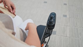 Woman maneuvering electric wheelchair control lever - Powered by Shutterstock - Get 15% off with code: PIKWIZARD15