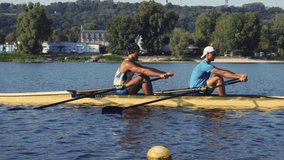 Rowing team training. Side view of 2 young caucasian male rowers, during a rowing practice, athlete sitting in a boat in the river Dnipro, rows through a calm water sunny day, autumn. 4k footage - Powered by Shutterstock - Get 15% off with code: PIKWIZARD15