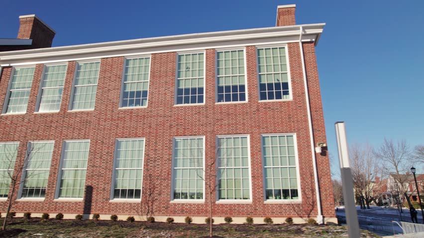 Driving past closed school and education brick building during a cold winter in Columbus Ohio as class is canceled and delayed by snow, ice, and low temperature weather from car pov point of view