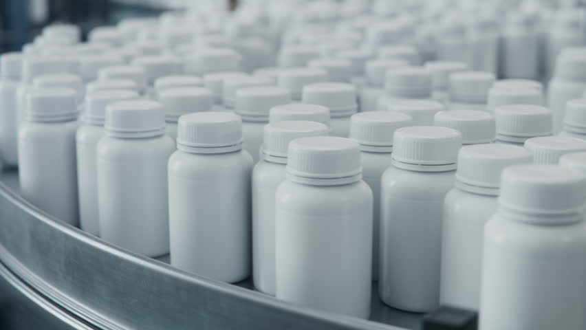 Close-up of White Medicine Bottles with Pills on Conveyor at Pharmaceutical Production Plant. Medication Manufacturing Process at Pharmaceutical Drug Factory 