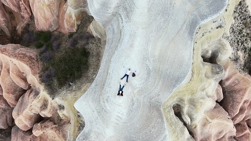 Aerial inspirational view couple lay on stunning colorful rock formations enjoy rose valley, Cappadocia. Freedom happiness couple in love travel concept. Travel holiday destinations Turkey