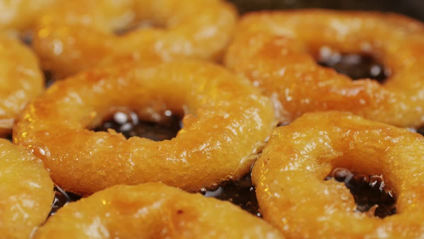 Fried crispy onion rings in a frying pan with oil close-up macro. Roasted onion rings for snacks at bar, cafe. Fast food. Delivery. Beer snacks