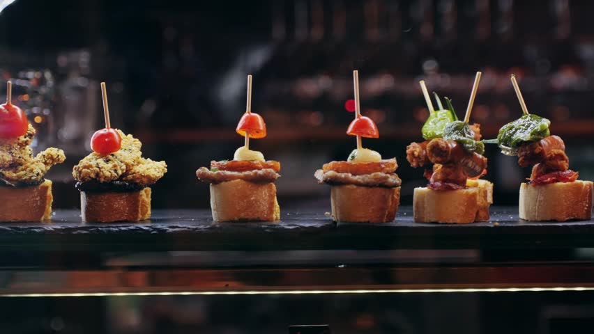 Italian or Spanish restaurant with traditional tapas pinchos food, Spanish cuisine, delicious tapas and cheese plate, bruschetta with cheese, olives dry tomatoes tasty sandwich bar appetizer, buffet