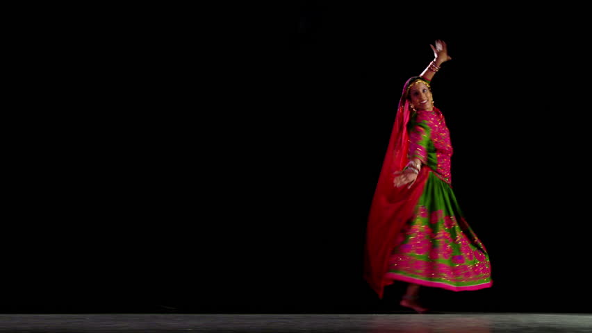 Indian girl in traditional dance costume finish her routine against a black