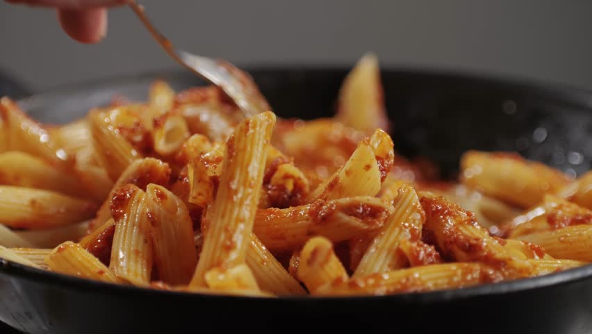 Cooking traditional arrabbiata pasta, penne with tomato sauce close-up. Cook classic homemade Italian tomato sauce for pasta and pizza in the pan. Chef cooks traditional Italian food. 