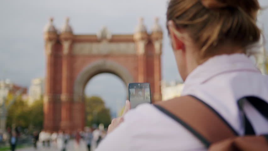 Man blogger making videos using selfie stick phone smartphone taking photo with dance for internet blog on street. Young guy tourist having video call on cellphone walking outdoors in Barcelona spain