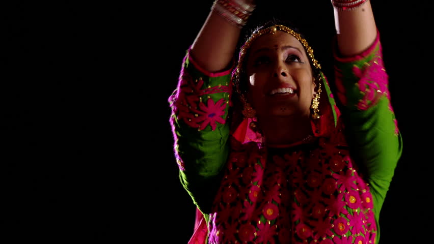 Indian girl in traditional dance costume dances against a black background.