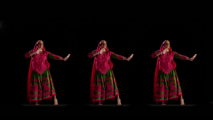 Indian girl in traditional dance costume dances against a black background. Full