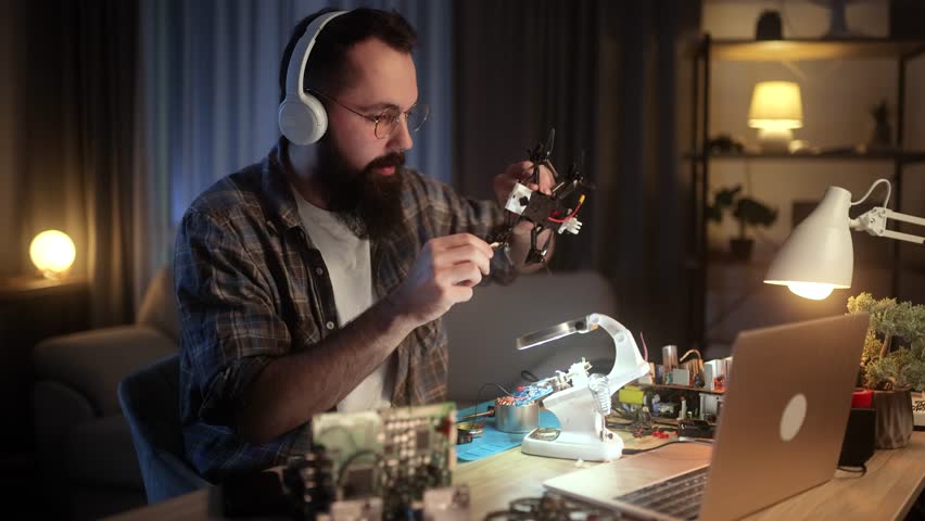 The young engineer is creating a video blog where he teaches the basics of soldering electronic boards. A man explains the process of creating an FPV drone
