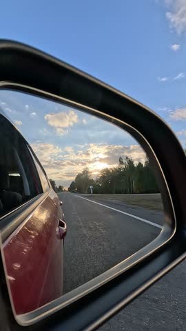 Automobile in motion. View in the rear view side mirror of a auto, driving a red car along the track