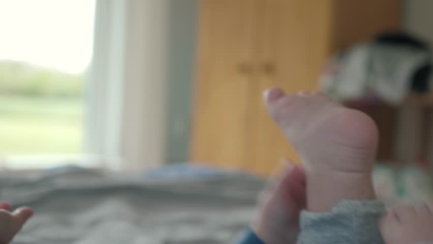 Little baby is joyfully engaging with their tiny feet while lying, close up. Infant showcasing their playful innocence, genuine curiosity, and carefree demeanor