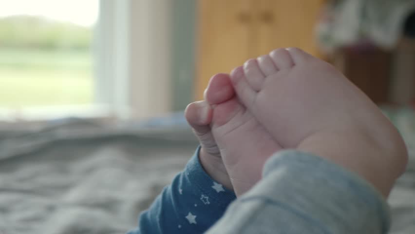 Little baby is joyfully engaging with their tiny feet while lying, close up. Infant showcasing their playful innocence, genuine curiosity, and carefree demeanor
