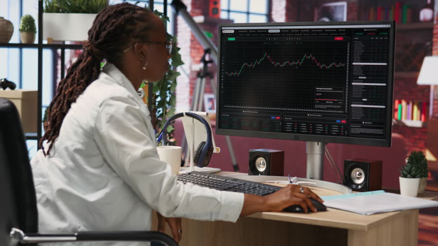 Frustrated day trader feeling upset, looking at PC screens showing falling stock prices, red charts and losses. Investor overwhelmed while looking at drop in stock exchange shares on monitor, camera B