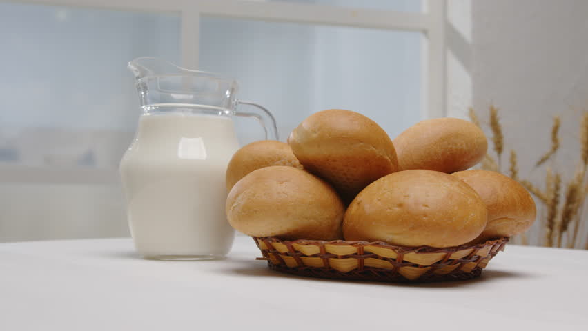 Bread buns with jug of milk on light background. Healthy organic breakfast. Farm natural products.