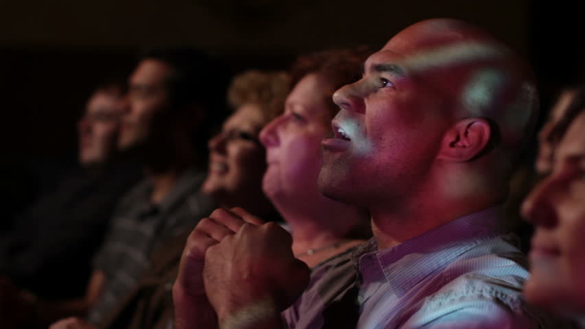 Young man has various reactions while watching a movie with a group of friends.