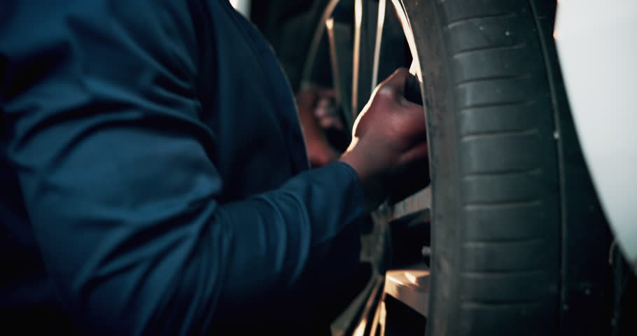 Black man, mechanic or change tire on car for repair service, maintenance or fix in professional garage. Hands, workshop or remove wheel of vehicle for inspection, check alignment or transport safety
