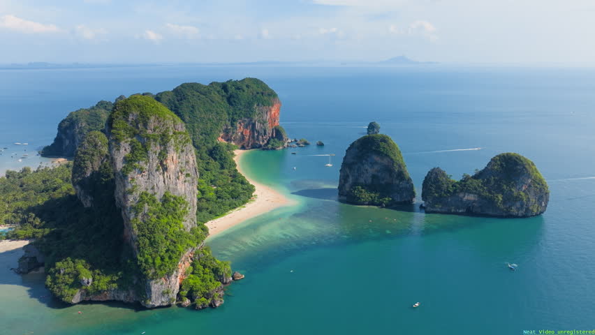 Witness the stunning aerial view of Krabis turquoise waters and limestone cliffs, with a longtail boat gliding through Thailands picturesque scenery, perfect for adventure and relaxation
