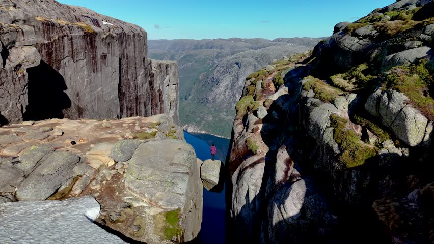 Norways spectacular cliffs, showcase stunning views of deep fjords and rocky formations. Experience natures grandeur in this stunning landscape.a women hiking Kjeragbolten Lysefjord Norway