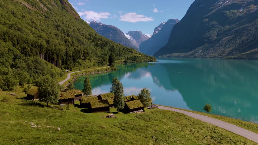 Discover breathtaking views of Norways lush mountains and crystal-clear waters. Nestled between towering peaks, charming wooden cottages of Lovatnet lake Norway 
