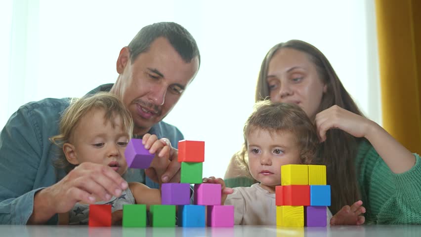 Family play with constructor home. Brother sister building blocks together. Parents guiding Brother sister constructor. Siblings learning play home. Family bonding time using constructor indoors.